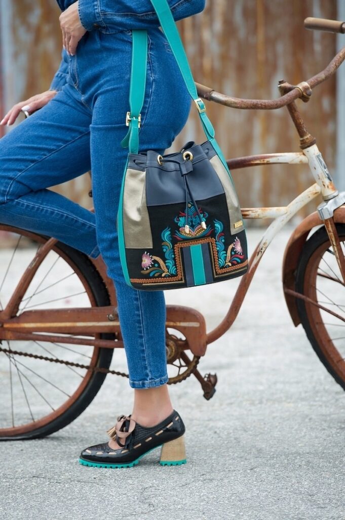 A woman with her bicycle and her colorful crossbody bag