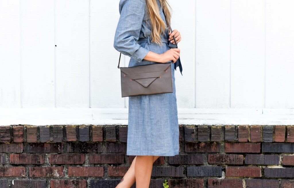 A woman wearing a small, gray, crossbody bag