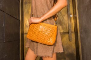 A woman wearing a crossbody bag made sustainably with eco-friendly materials